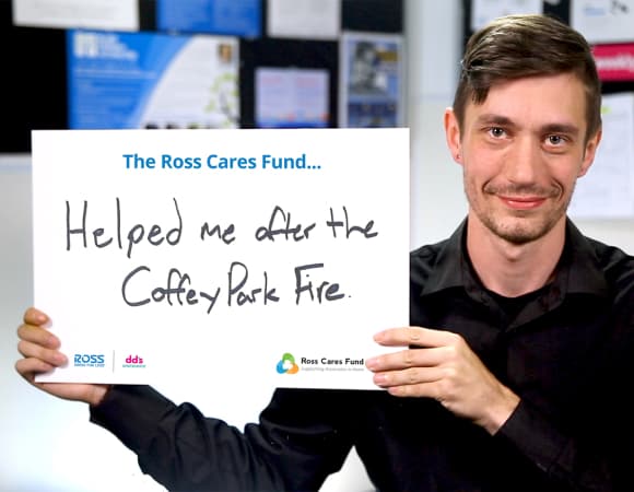 Associate holding a sign that reads The Ross Cares Fund helped me after the Coffey Park Fire.